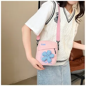 Detalle de primer plano del bolso bandolera rosa con flor de cuadros azul