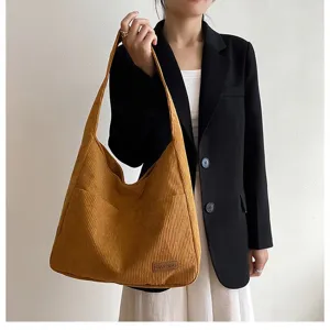 Large mustard yellow corduroy tote bag with side pocket and brand label, detail view.