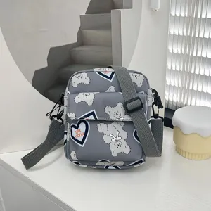 Detalle de los estampados de osito y corazón en un bolso bandolera de nylon gris claro