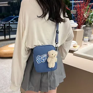 Bolso bandolera de nailon azul con osito de peluche blanco usado por una modelo