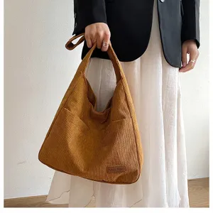 Close-up view of a brown corduroy tote bag featuring textured stripes and a small logo tag
