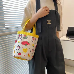 Cute cartoon canvas lunch bag with rabbit prints carried by a model in a casual setting.