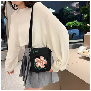 Primer plano de un bolso bandolera de lona negra con flor de cuadros para uso casual