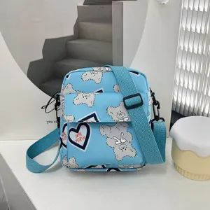 Vista detallada de un bonito bolso bandolera de nailon azul con oso de peluche y corazones