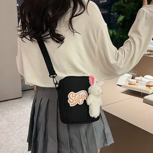 Primer plano de bolso bandolera negro de estilo japonés con adorable conejo de peluche.