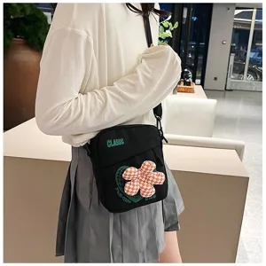Vista detallada de un bolso bandolera preppy negro con una flor de cuadros en 3D
