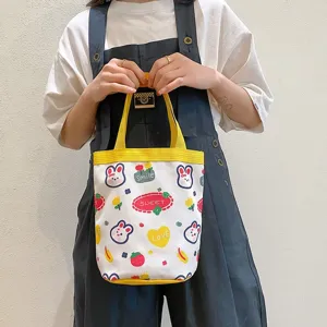 Close-up detail of cute cartoon canvas handbag featuring rabbit and flower patterns