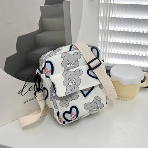 Vista detallada del bolso bandolera de nailon con estampado de osos y motivos de corazones.