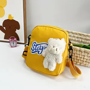 Vista detallada de un bonito bolso bandolera de nailon amarillo con osito peluche