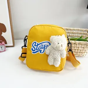 Detalle de bolso de nailon amarillo con osito de peluche blanco y parche Stayin