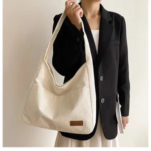 Detail of off-white corduroy tote bag shown on model with black blazer.