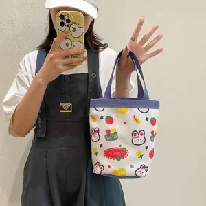 Close-up of a cute cartoon canvas lunch bag with rabbit prints held by a model.