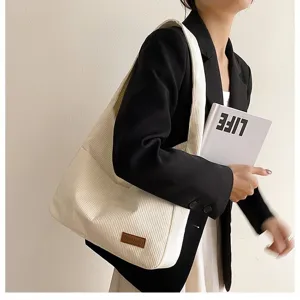 Detailed view of cream corduroy tote bag worn with a black blazer for a stylish daily look