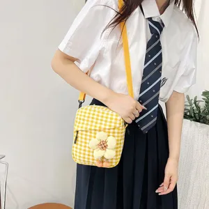 Detalle de un bolso bandolera de cuadros amarillos con flor de peluche llevado por una modelo
