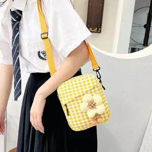 Detalle de un pequeño bolso bandolera de cuadros amarillos con una flor de peluche
