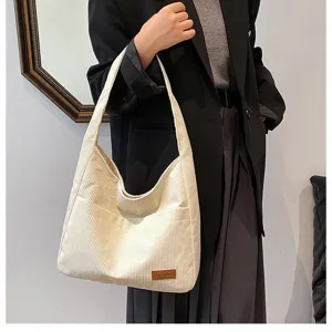 Close-up of white corduroy tote bag with textured stripes and small leather patch