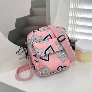 Primer plano del bolso bandolera de nailon rosa con estampados de osos y corazones.
