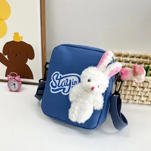 Vista detallada del bolso bandolera azul con un lindo adorno de conejo de peluche.