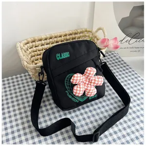Primer plano de un bolso bandolera negro con detalle de flor de cuadros 3D