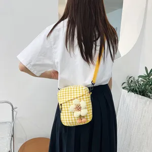 Mini bolso bandolera de cuadros amarillos con detalle de flor de felpa en modelo.