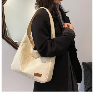 Detail view of off-white corduroy shoulder bag showing texture on a female model