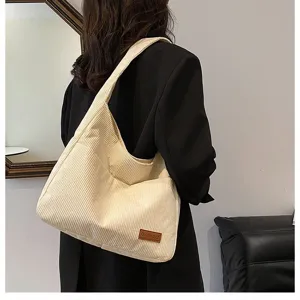 Stylish back view of a model carrying a large capacity cream corduroy hobo shoulder bag