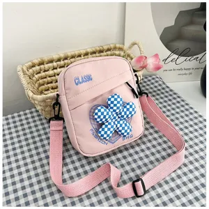 Vista detallada de un bolso bandolera rosa estilo universitario con flor de cuadros