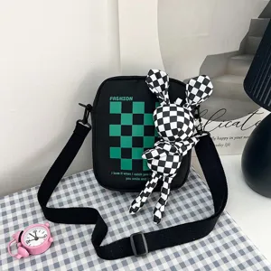 Detalle del bolso bandolera negro a cuadros con accesorio de conejo de peluche