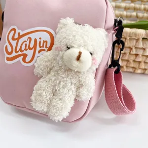Detalle de un lindo bolso bandolera de nailon rosa con un oso de peluche blanco