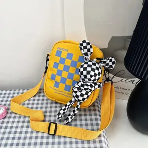 Detalle de bolso bandolera de lona amarilla con colgante de muñeco de conejo