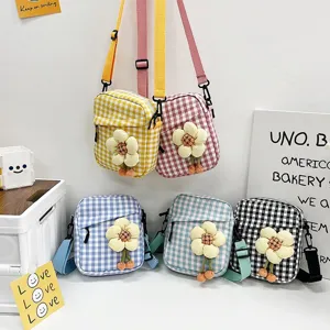 Exhibición detallada de varios mini bolsos bandolera de cuadros con dijes de flores