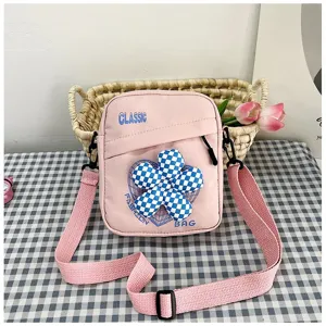 Bolso bandolera rosa estilo escolar con flor decorativa a cuadros azules y texto clásico