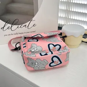 Detalle de un bolso bandolera de nailon rosa con estampados de osos y corazones para niñas.