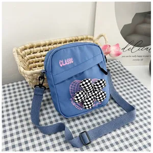 Detalle del bolso bandolera de lona azul con corazón y adorno de flor a cuadros