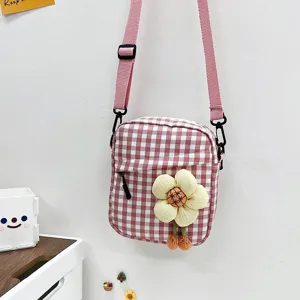 Detalle de mini bolso bandolera rosa a cuadros con un lindo colgante de flor de peluche