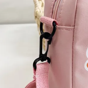 Detalle de primer plano del gancho de plástico negro y la correa de nailon rosa del bolso bandolera