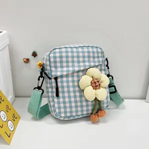 Detalle del mini bolso bandolera de cuadros azules con gran accesorio de flor.