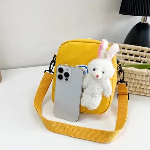 Lindo bolso bandolera de conejo amarillo junto a un smartphone para ver el tamaño