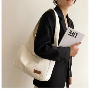 Detail view of a stylish cream white corduroy tote bag shown worn over the shoulder