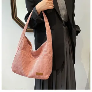 Detailed view of a pink corduroy tote bag styled with a professional black blazer.