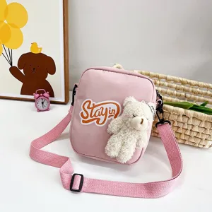 Detalle del bolso bandolera de nailon rosa con peluche de oso blanco y estampado Stayin