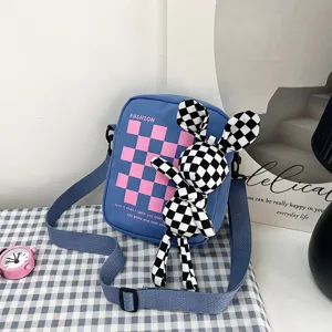 Bolso bandolera azul a cuadros con un muñeco de conejo a cuadros blancos y negros.