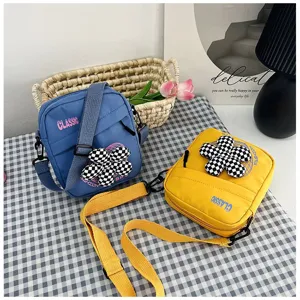 Pareja de pequeños bolsos de lona azul y amarillo con dijes de flores decorativos