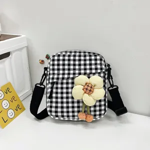 Detalle del mini bolso bandolera a cuadros con una gran flor decorativa de peluche