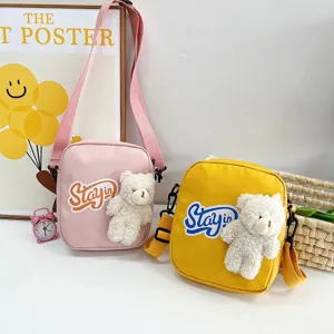 Vista detallada de bolsos bandolera de nailon con oso de peluche en rosa y amarillo