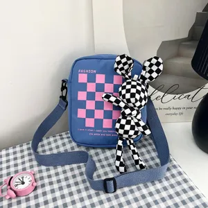 Primer plano de bolso bandolera azul con muñeco conejo a cuadros en ambiente cotidiano