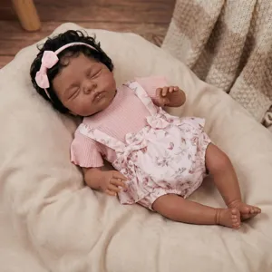 Detailed view of realistic sleeping reborn baby doll Irys wearing a pink floral romper and bow