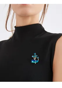 Close-up detail of a cute blue whale brooch with blue crystal balloons on a model.