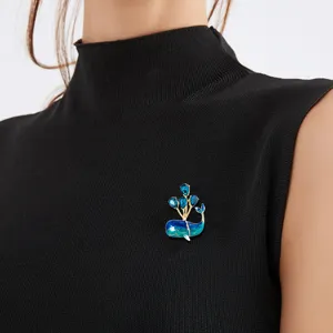 Adorable blue whale brooch with crystal balloons displayed on a black sleeveless top