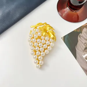 Detaillierte Nahaufnahme einer goldenen Vintage-Traubenbrosche mit eleganten weißen Perlen